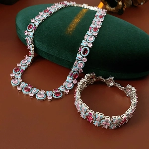 Détail macro d'une parure vintage en argent avec pierres roses et rouges sur velours
