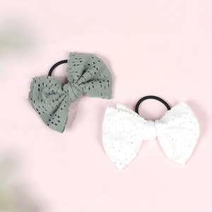 Close-up of green and white hollowed-out fabric bow hair ties with black elastic bands
