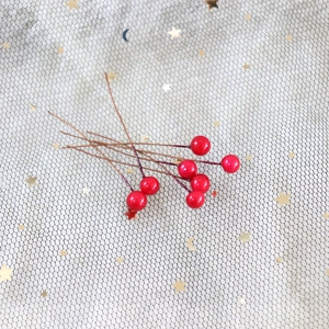 Macro shot of eight millimeter glossy red artificial berries on branches for wedding decor