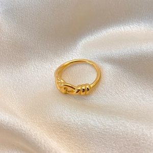 Anello a nodo dorato minimalista in acciaio inossidabile su elegante sfondo di seta