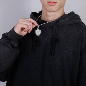 Detail of vintage shield pendant with woven texture on braided steel chain for men