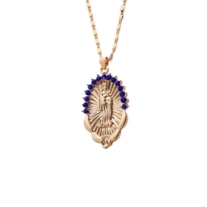 Macro shot of gold Virgin Mary oval pendant with sparkling blue rhinestones inlay