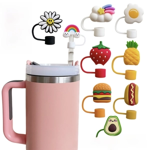 Various cute silicone straw toppers showing daisy and fruit designs on a pink cup