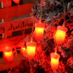 Detail of red Christmas glove LED string lights with snowflake pattern on snowy background