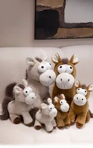 Détail de peluches de poney drôles de différentes tailles et couleurs sur un canapé crème