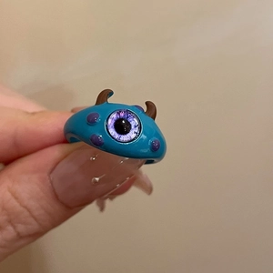 Detailed close-up of blue monster character ring with purple eye and brown horns