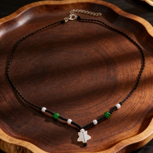 Detail view of a woven necklace featuring a white star pendant with green jade beads