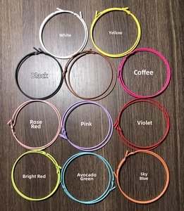 Détail de boucles d'oreilles créoles mates en onze couleurs sur une surface en bois sombre