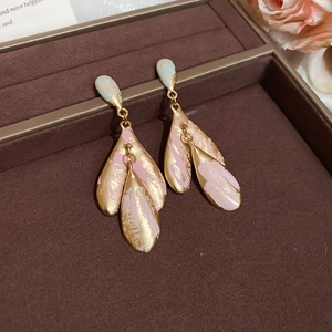 Close-up of gold leaf earrings with pink and cyan enamel in a brown velvet jewelry box