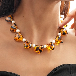 Macro detail of acrylic heart-shaped beads with leopard print and faux pearls on a necklace