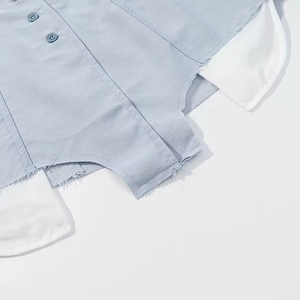 Détail de l'ourlet effiloché et de la patte de boutonnage sur robe chemise à carreaux bleu clair