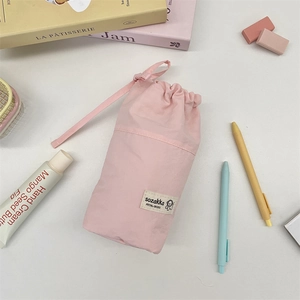 Pink drawstring stationery pouch with woven label on a desk with cute accessories