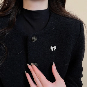 Close-up of sparkling bow brooch with cubic zirconia on a black tweed jacket lapel