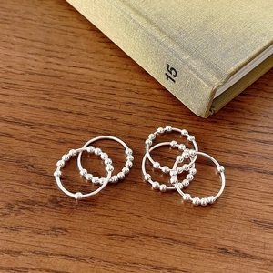 Detail of five minimalist 925 silver beaded rings on a rustic green book and wood background