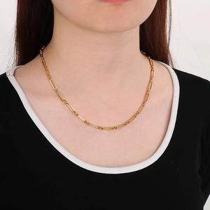 Gros plan d'un mannequin portant un collier à maillons trombones dorés au design chic