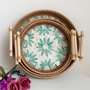 Detail of three-piece nested rattan trays with green shell flower patterns and wooden handles