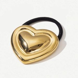 Detail shot of a double-layered 18k gold heart-shaped metal charm on a black elastic hair tie