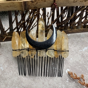 Macro view of handmade black crescent moon hair comb with raw orange crystal points