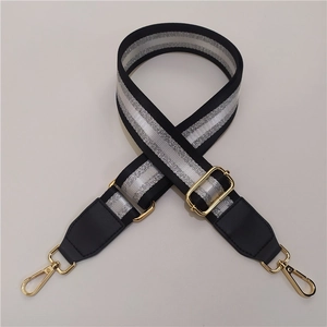 Detail of adjustable black and silver striped bag strap with gold metal lobster hooks