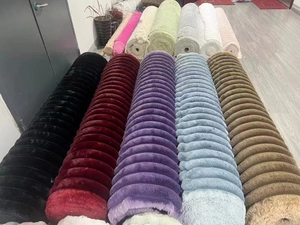 Rolls of colorful striped faux fur fabric in various shades on display in warehouse