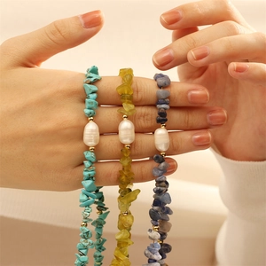 Detailed view of three beaded bracelets with baroque pearls and natural stone chips on a hand