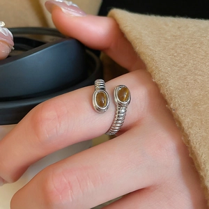 Detail of silver crossover ring with amber stones worn by model in cozy autumn style