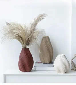 Détail de trois vases en céramique aux rayures texturées en rouge, beige et blanc crème
