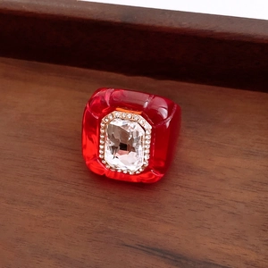 Close-up of a vintage red resin hexagonal ring with crystal centerpiece on a wooden tray