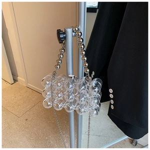 Detail of transparent acrylic bubble evening bag with pearl handle and metal chain strap