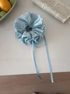 Close-up of light blue lace scrunchie with long ribbons and elegant floral embroidery