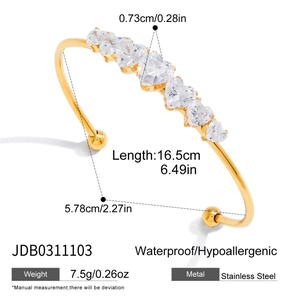 Detail view of gold stainless steel open bangle with dimensions and seven heart zircons