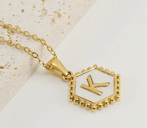 Detailed shot of hexagonal 18K gold plated K pendant necklace with white shell inlay