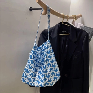 Detail of artistic floral cotton tote bag with blue cat print on wooden branch hanger