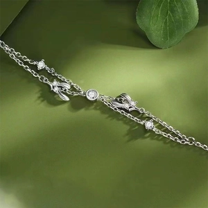 Elegant silver mistletoe bracelet with zircon vines and bow pendant on green backdrop
