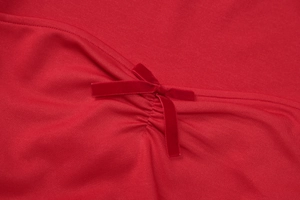 Détail de la robe en tricot rouge avec nœud en velours et design de texture froncée