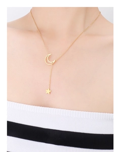 Detailed view of the gold star and crescent moon Y-pendant necklace on a collarbone
