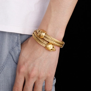 Detail of twisted steel cable bracelet with gold skull heads on a male wrist