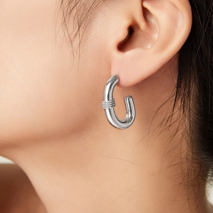 Polished silver U-shaped hoop earrings with woven texture detail on model