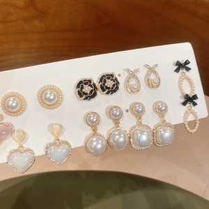 Detail view of pearl and black flower earring set with elegant bow and heart pendants