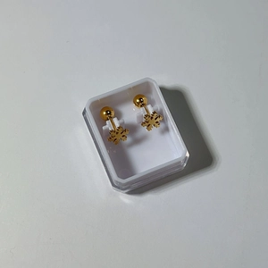 Detail view of gold snowflake stud earrings with ball screw backs in a storage box