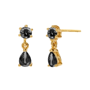 Macro detail of gold earrings featuring black teardrop crystals and faceted round studs