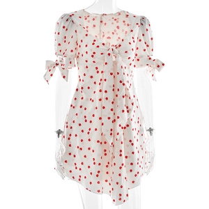 Détail d'une robe blanche à pois avec manches bouffantes et poignets à nœuds délicats