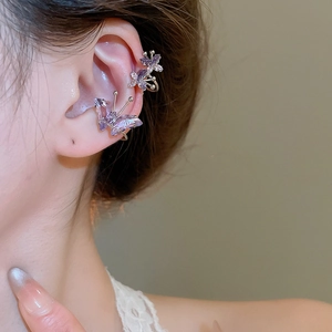 Macro detail of purple zircon butterfly ear clips on a female ear with a golden finish