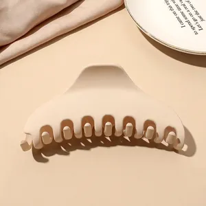 Macro shot of large matte beige shark hair claw clip with rounded teeth on fabric