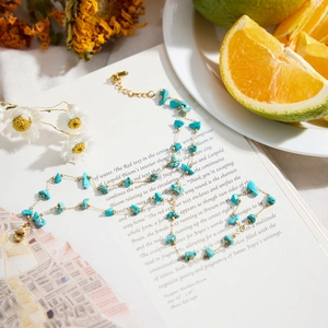 Natural turquoise bead bracelet with gold chain displayed on an open book page