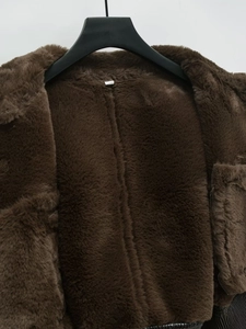 Close-up of fluffy dark brown faux fur jacket showing thick plush texture and collar detail
