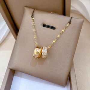 Macro detail of gold double ring pendant with crystals on beige silk cushion