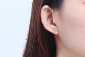 Close-up of silver titanium steel arrow stud earring worn on model ear