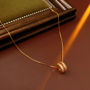 Detail of gold plated necklace with zircon cylinder pendant on premium leather background