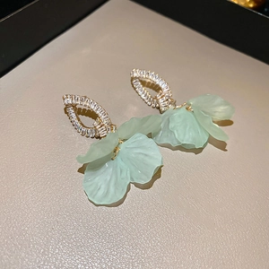 Macro detail of mint green flower earrings with gold petals and sparkling crystals